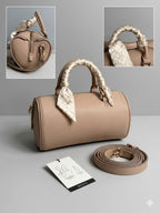 Beige handbag with decorative handles on a gray background