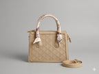 Beige handbag with a matching strap on a gray background
