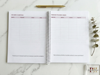 Open planner with income and earnings tracker on a marble surface with a pen and plant.