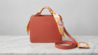 Shop this elegant coral pink structured satchel handbag featuring gold-tone hardware, a detachable crossbody strap, and matching card holder. Perfect for work, travel, and everyday style.