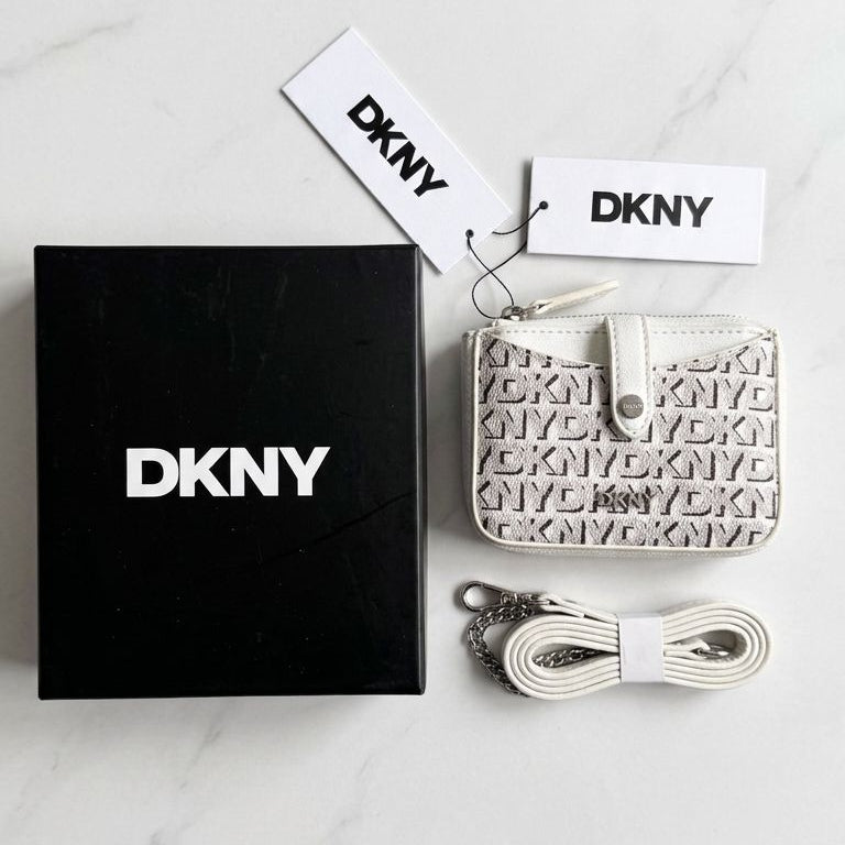 DKNY wallet with packaging and accessories on a marble surface