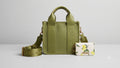 Green handbag with matching strap and small pouch on a light gray background