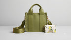 Green handbag with matching strap and small pouch on a light gray background