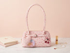 Pink handbag with cherry design on a light pink background