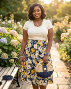 Woman in a floral skirt and white top standing in a garden