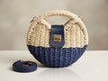 Woven handbag with a blue bottom section and beige top section on a neutral background